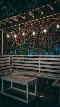 Custom-built outdoor dining table with matching benches under a pergola.