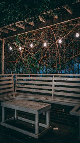 A cozy wooden outdoor dining table set under string lights in a garden.