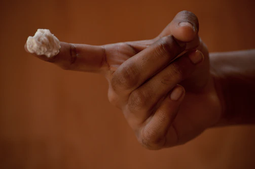 Aurora Pink cream texture shown on a fingertip, emphasizing its smooth and creamy consistency.