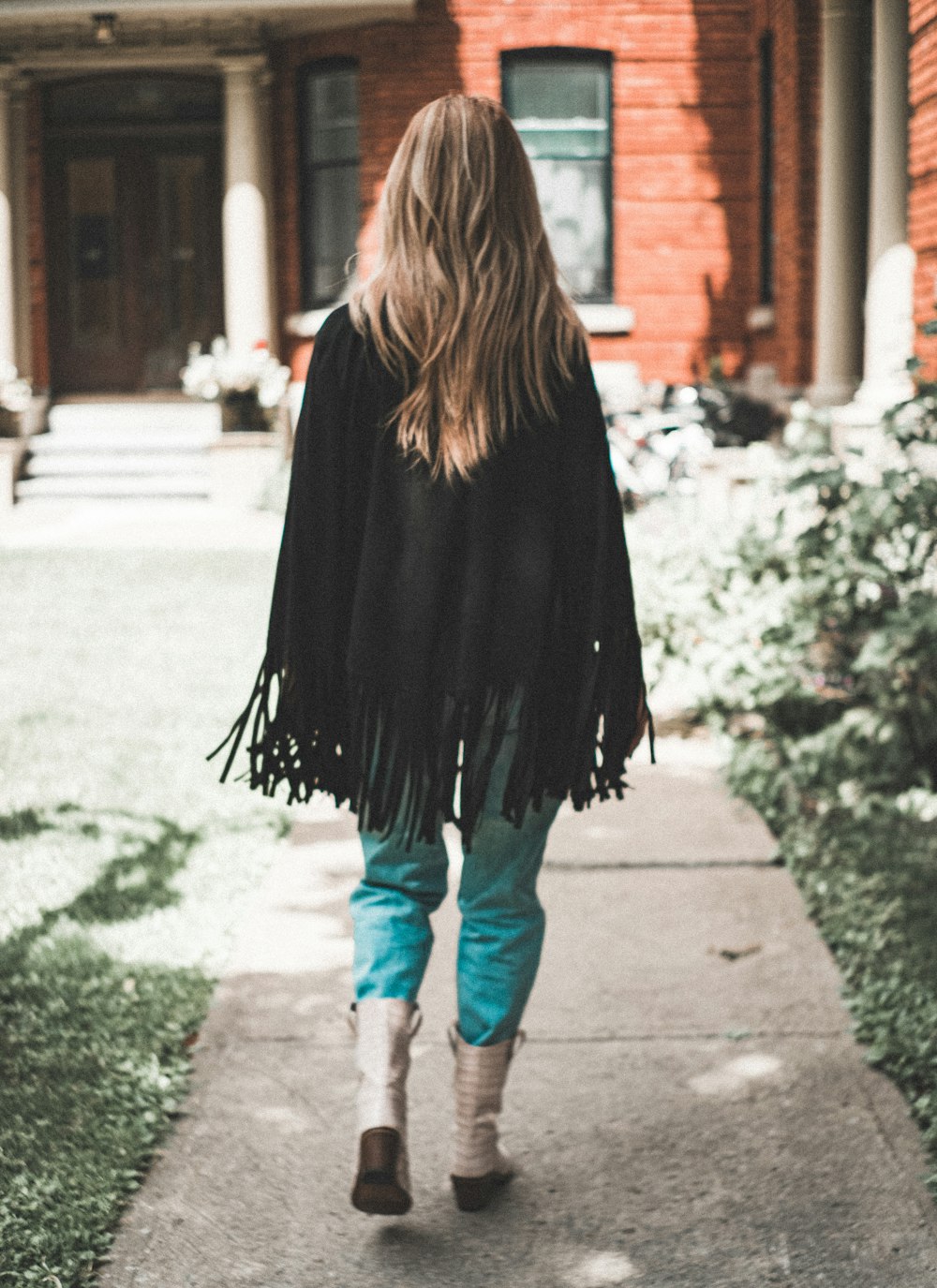 woman wearing black fringe cardigan walking on pathway
