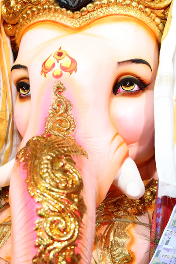 Close-up of a beautifully detailed handcrafted sadu mati Ganpati idol glowing softly in warm festival light.