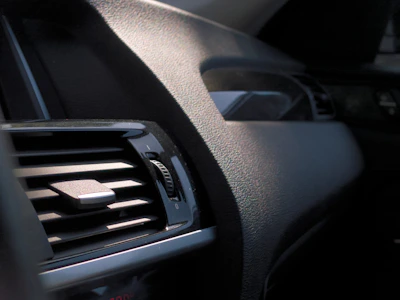 Close-up of a technician carefully wiping a car dashboard with a soft cloth.