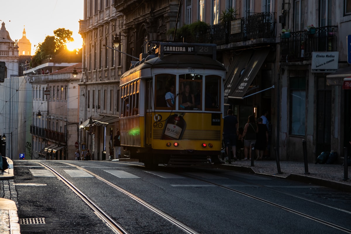 People riding a yellow tram down a street in Lisbon, Portugal