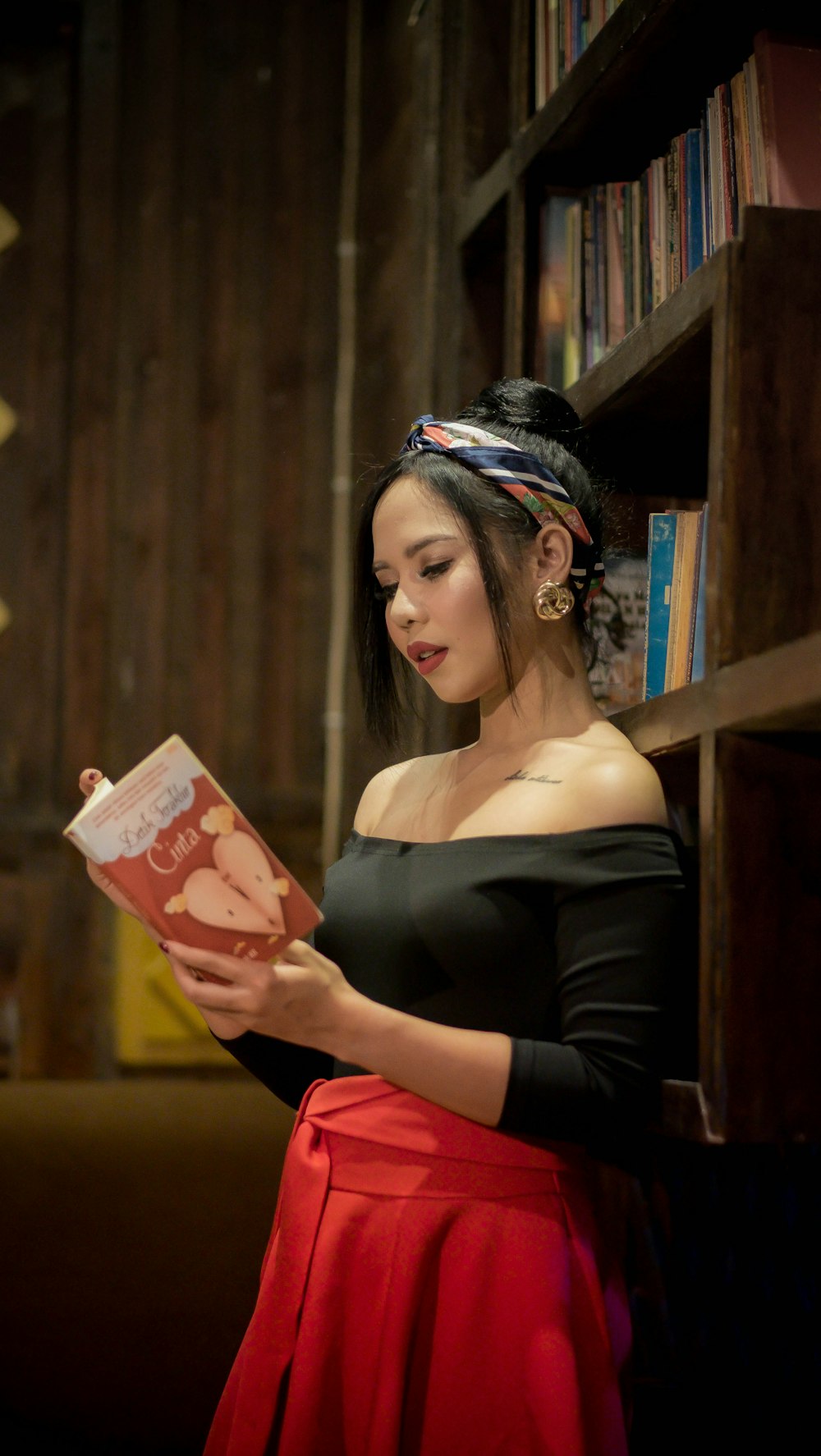 woman wearing black open-shoulder 3/4-sleeved top reading book