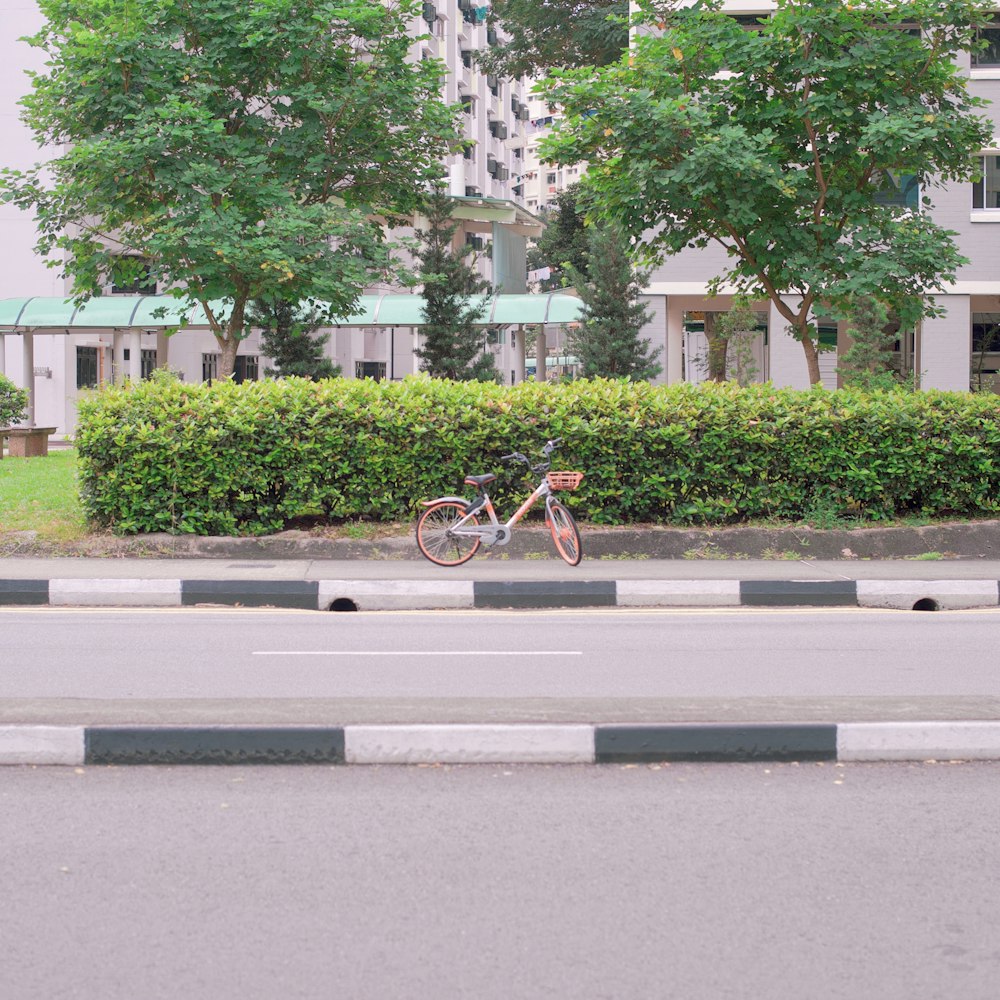 orange and black bicycle parked on road at daytime