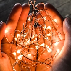A pair of hands gently holding a glowing red thread symbolizing connection.