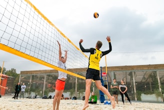 man wearing yellow and black long-sleeved shirt playing volleyball