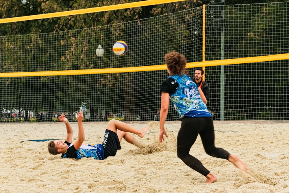 man and woman wearing blue and black jersey playing beach volleyball