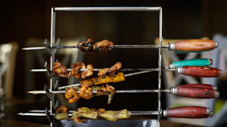 Variety of colorful skewers with meat and vegetables roasting on a traditional barbecue.