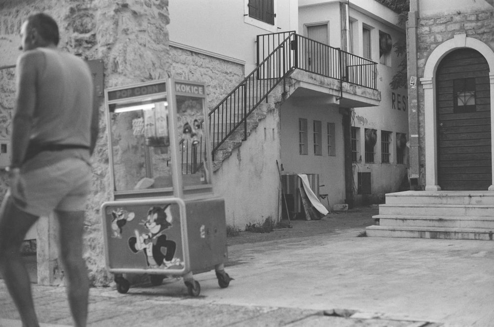 grayscale photography of man walking near food stall