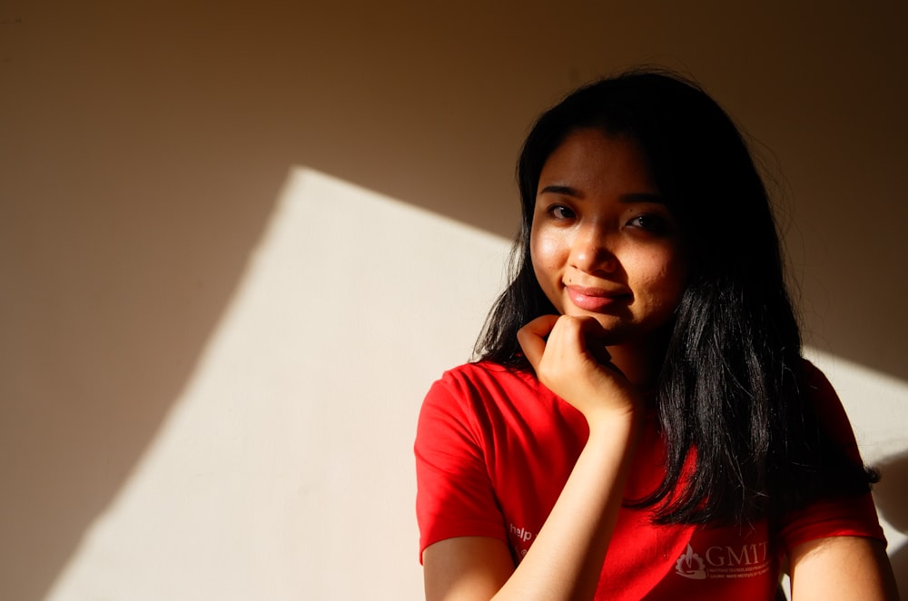 mujer con camisa roja sentada al lado de la pared