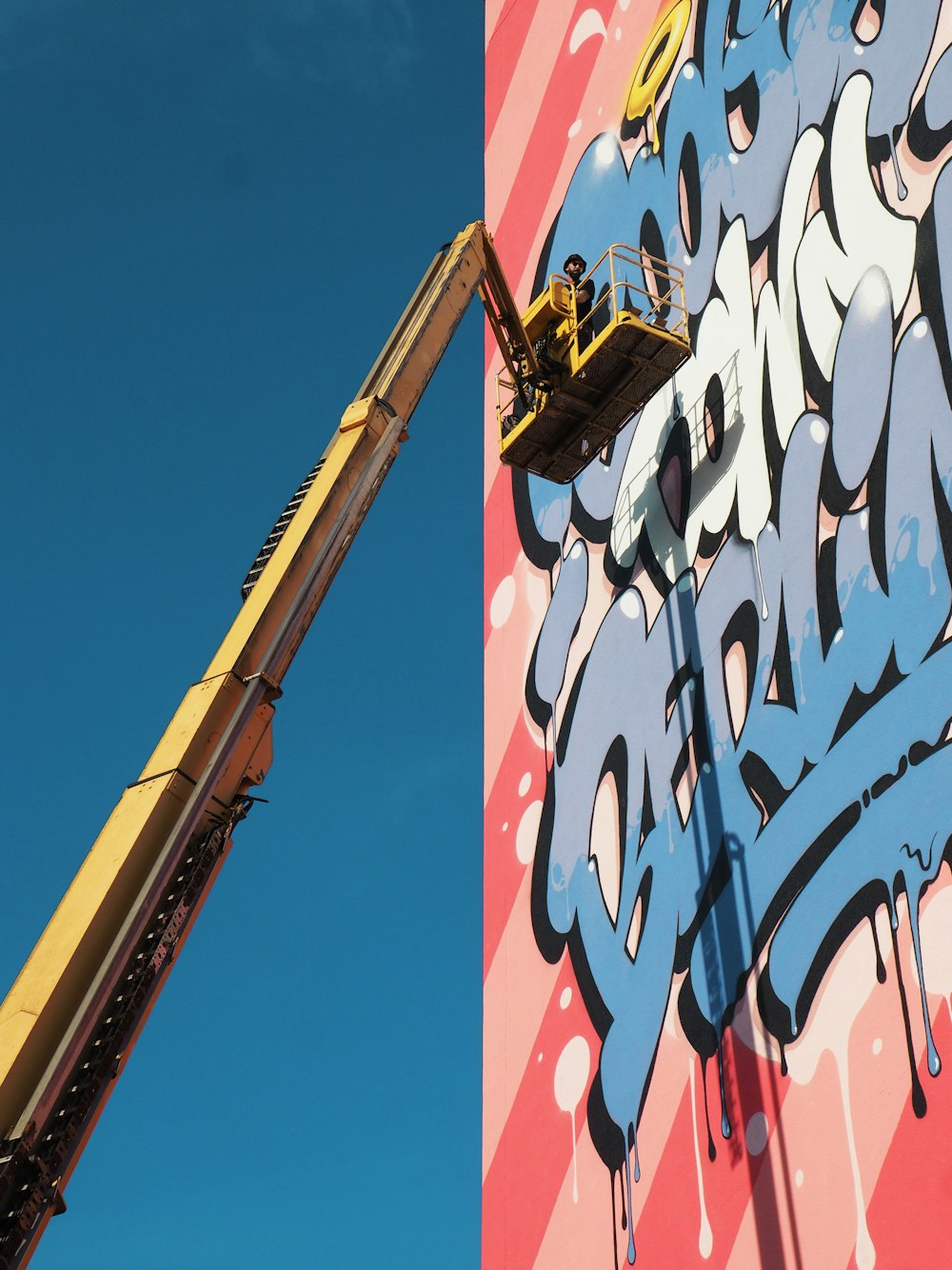 yellow bucket truck near graffiti wall art during daytime