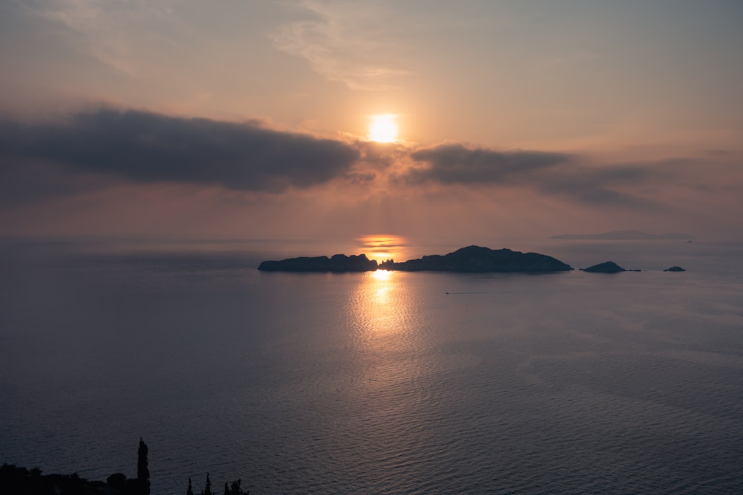 silhouette of island surrounded by sea water during dusk