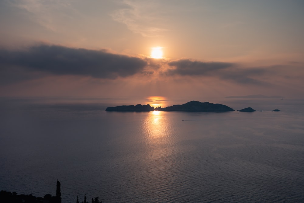 silhouette of island surrounded by sea water during dusk