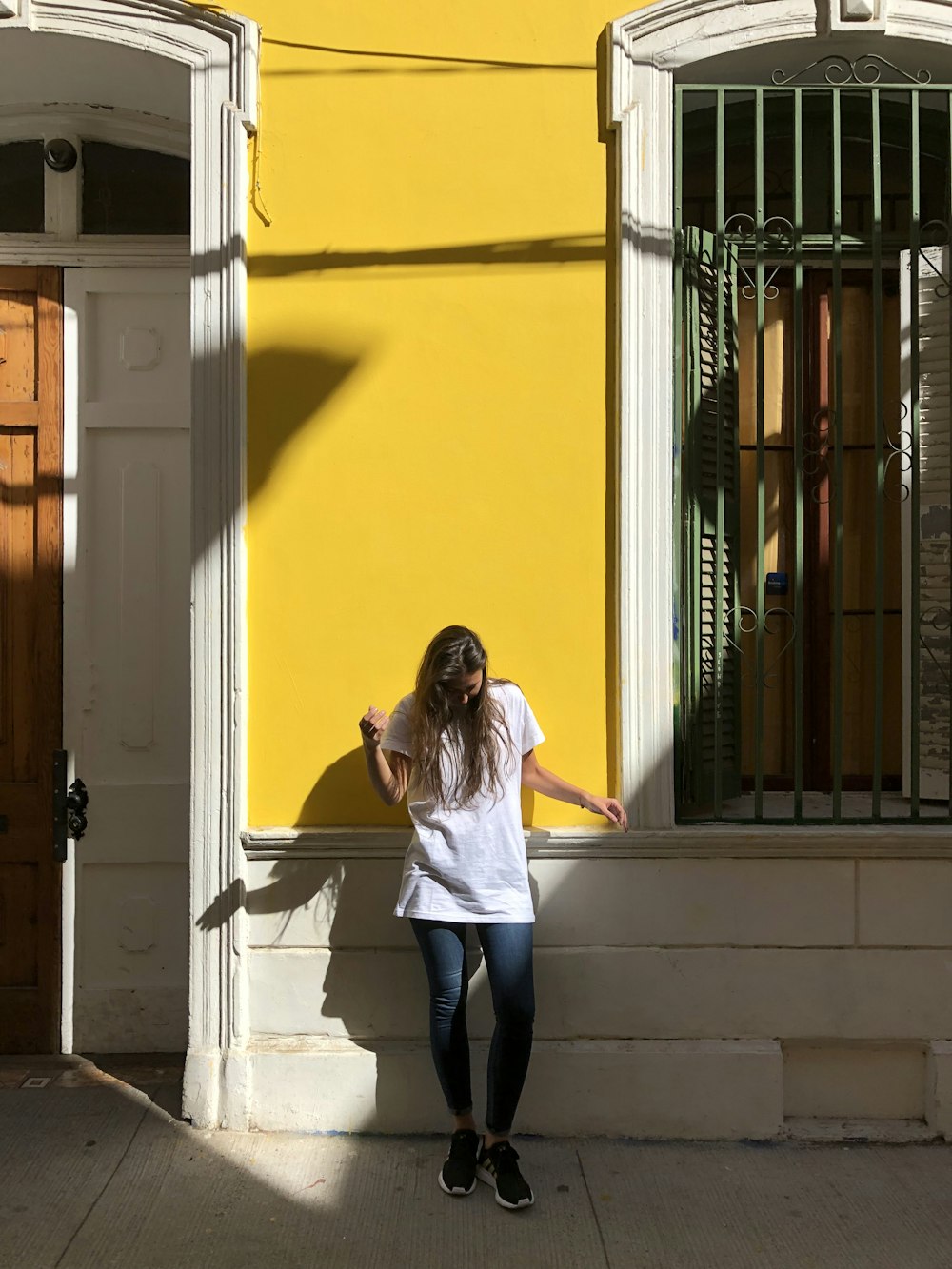 woman wearing white t-shirt leaning on wall
