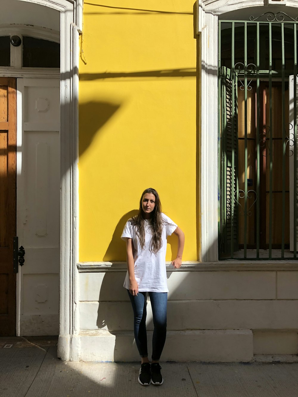 woman leaning back on building wall during day