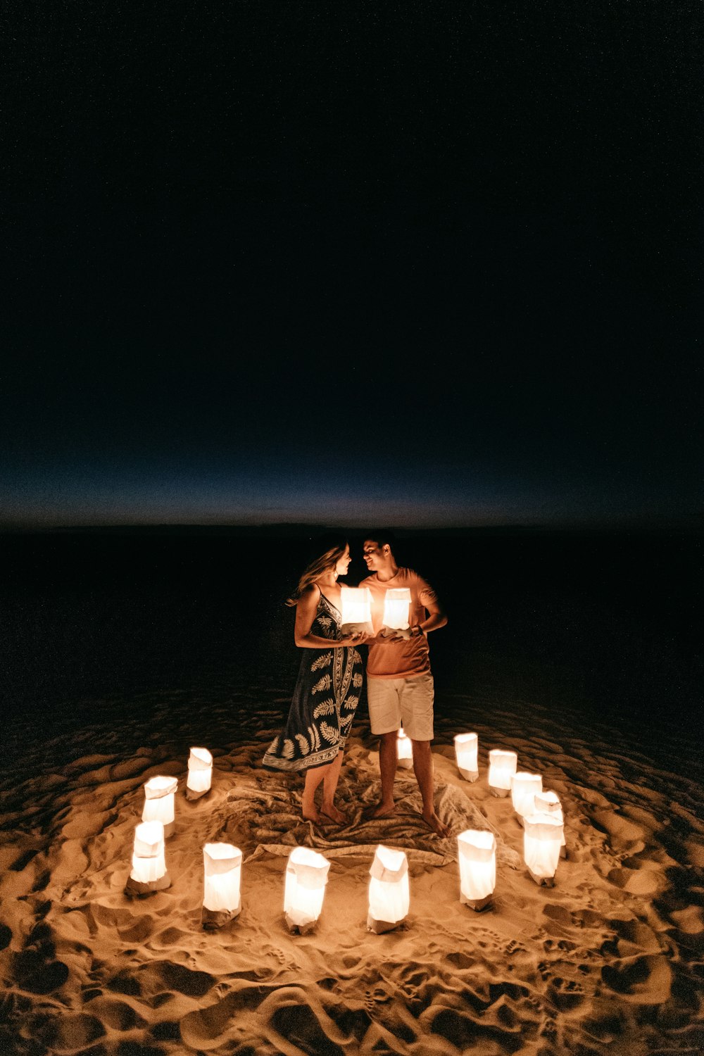 man and woman standing outdoors holding paper lanterns