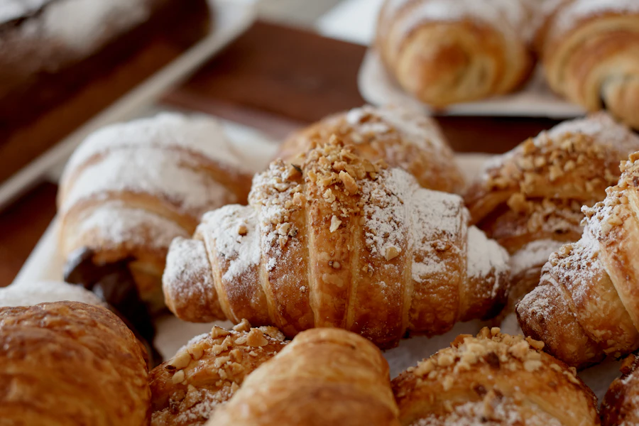 Flaky croissants dusted with icing sugar and nuts