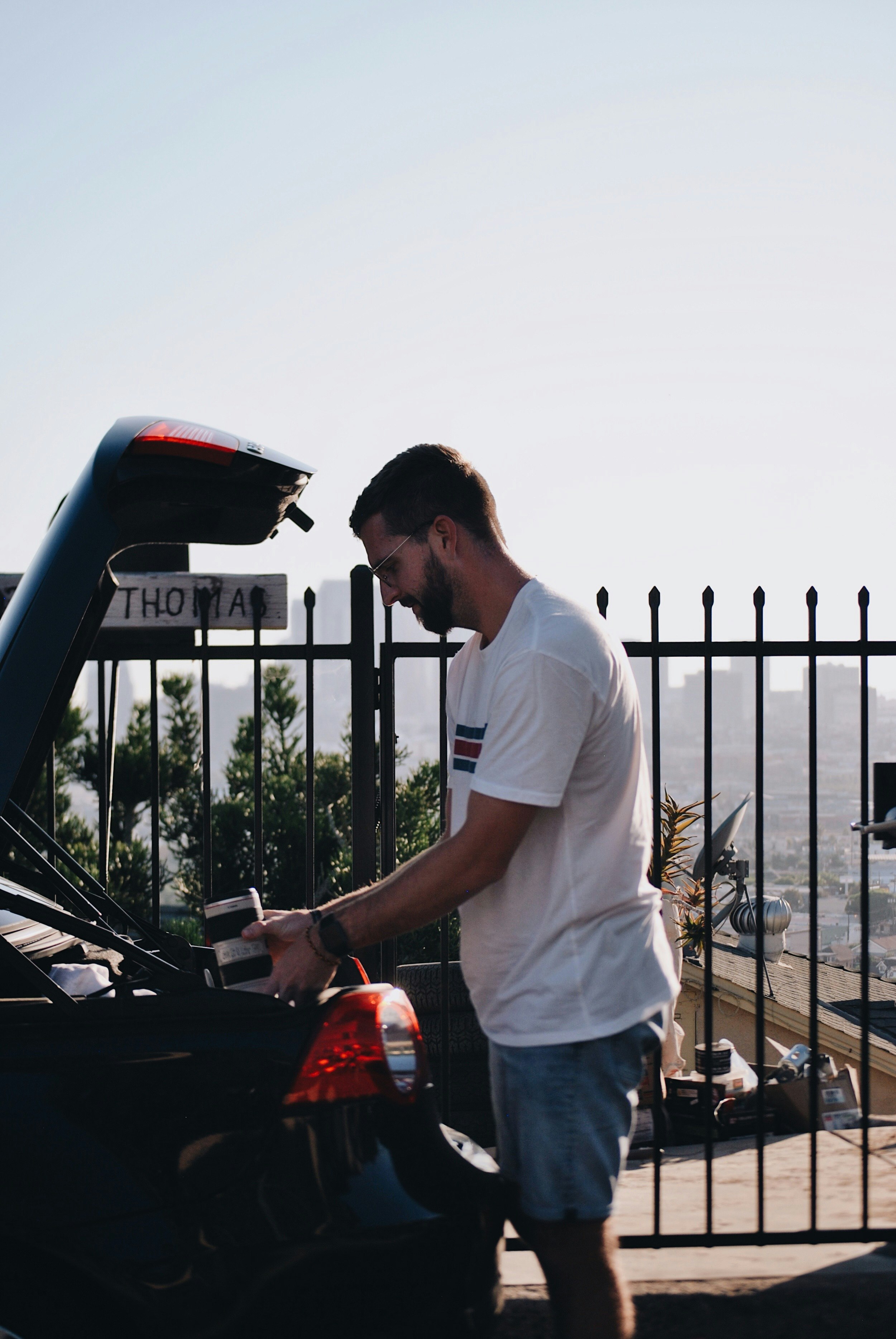 man holding camera lens standing in front of vehicle