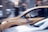 A yellow taxi is in motion on a city street, captured in a side profile with a driver visible inside. The background appears blurred, indicating movement and speed. The taxi has a sign on its side indicating independent ownership.