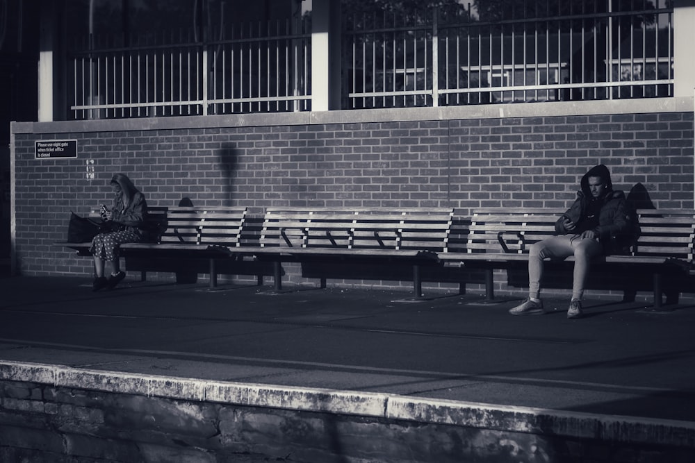 man and woman sitting on bench