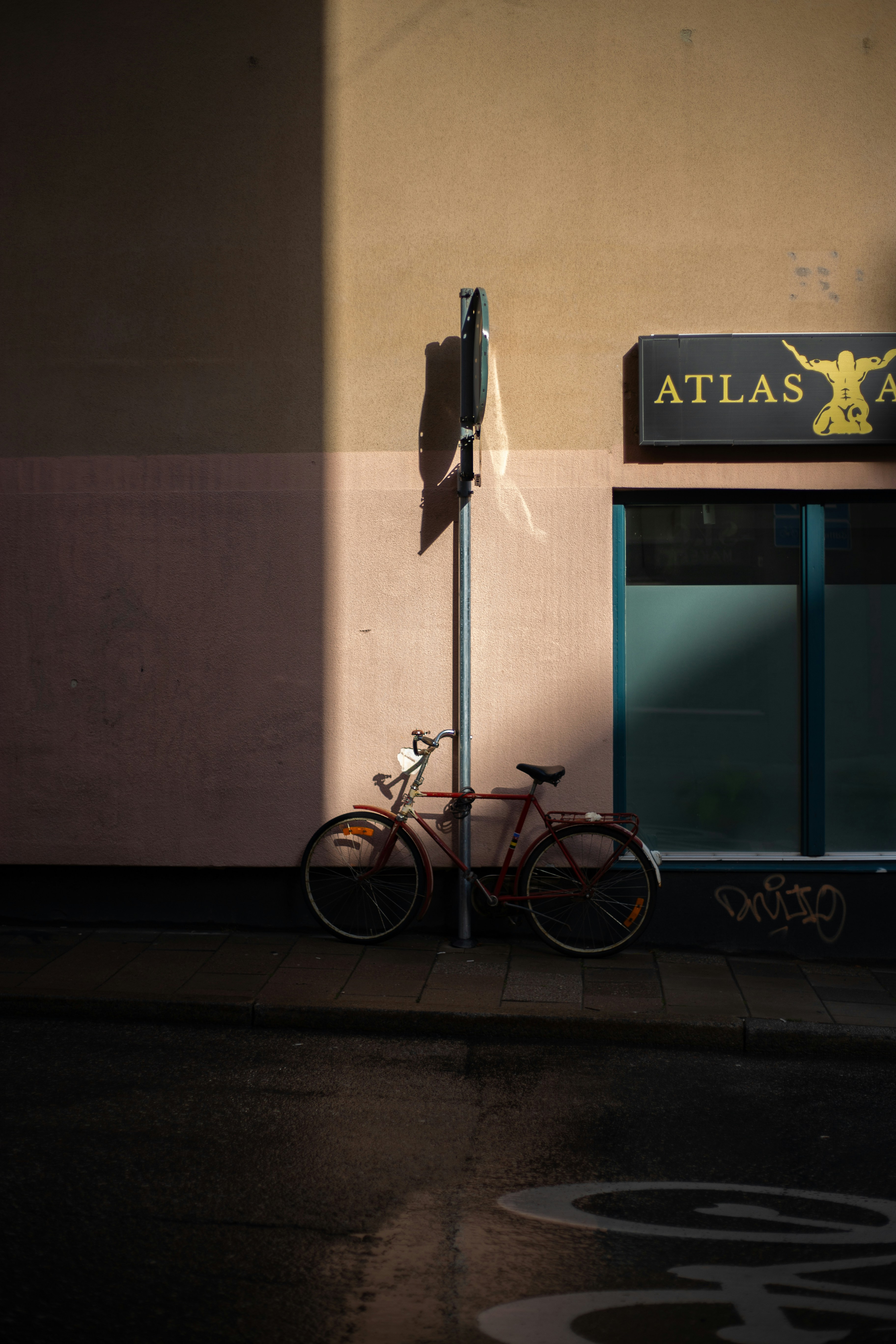 Bicicleta roja estacionada al lado del poste