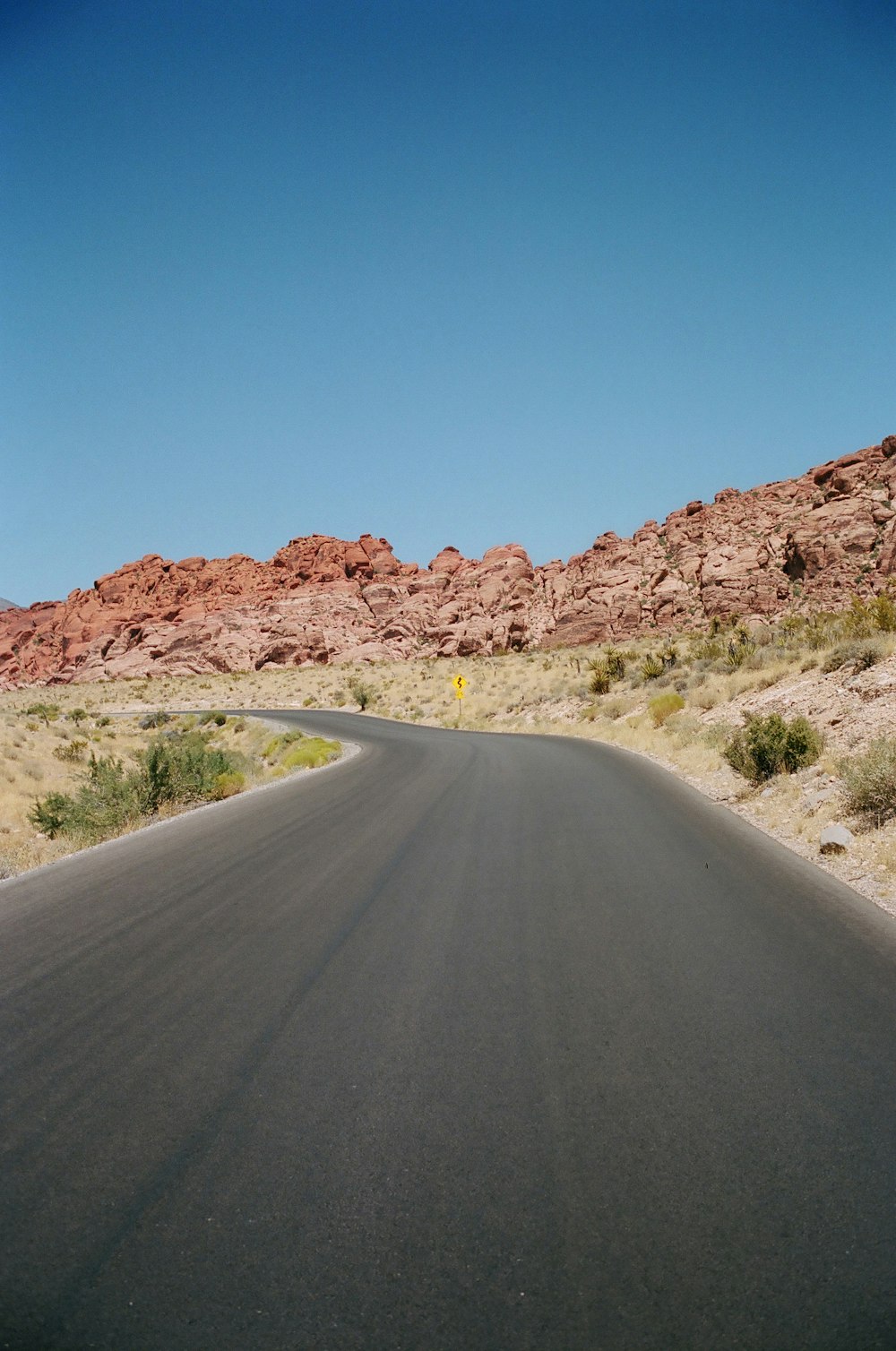 gray concrete road with no vehicle viewing mountain during daytime