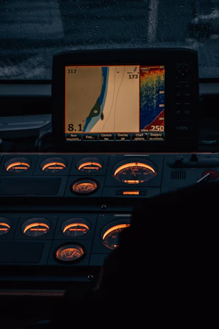 Close-up of a high-tech AIS navigation device glowing softly on a yacht's control panel at dusk.