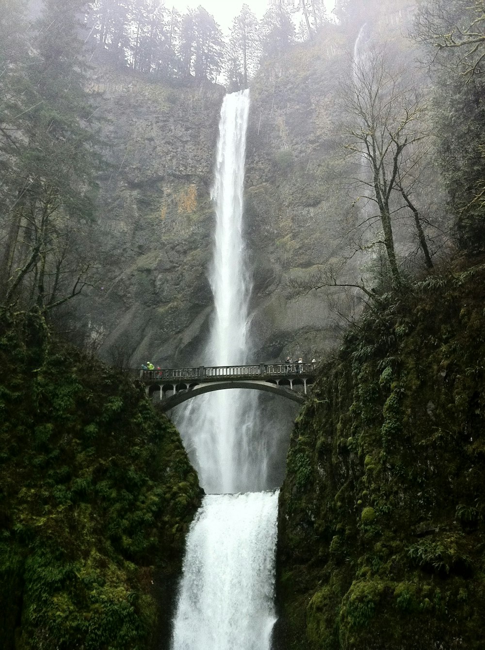 ponte in cemento grigio davanti alle cascate d'acqua