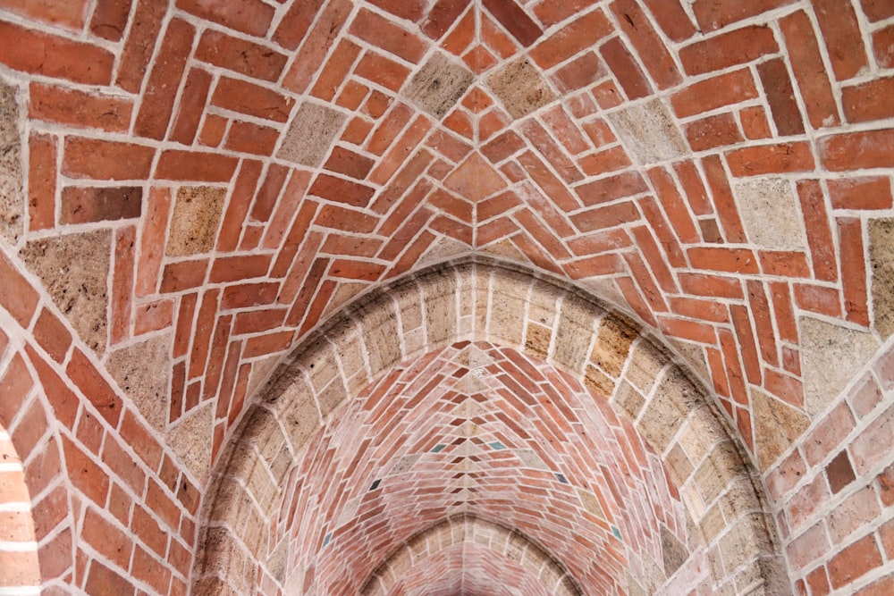 an archway in a brick building with a clock on the wall