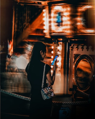 time lapse photography of woman holding smartphone in front of carousel