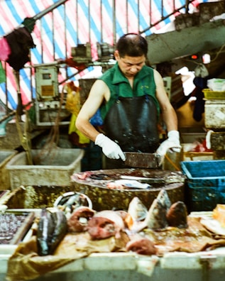 A vendor at Maria Helena's peixaria preparing fish for sale behind the counter.