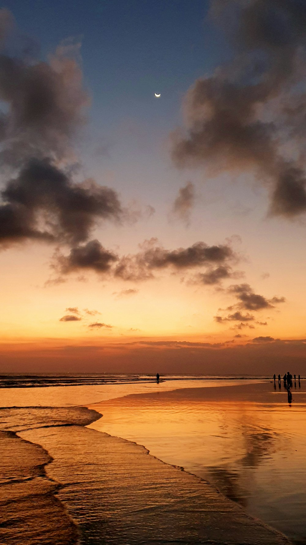 people near seashore under brown and orange skies