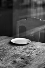 photo en noir et blanc de l'intérieur d'une maison avec une assiette blanche vide sur une table