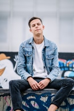 man wearing white crew-neck shirt and blue faded denim jacket