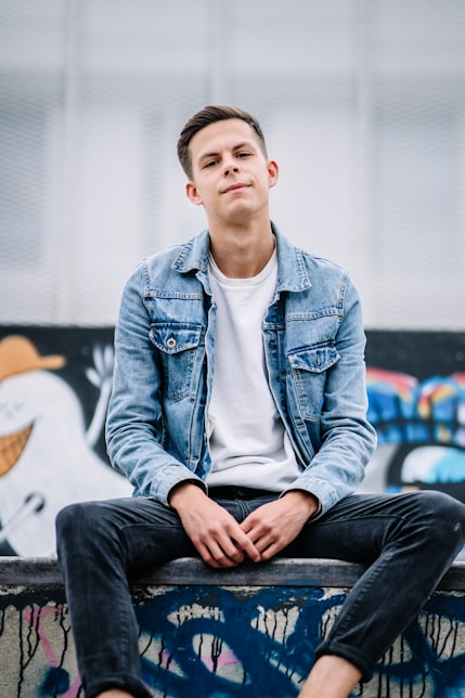 man wearing white crew-neck shirt and blue faded denim jacket