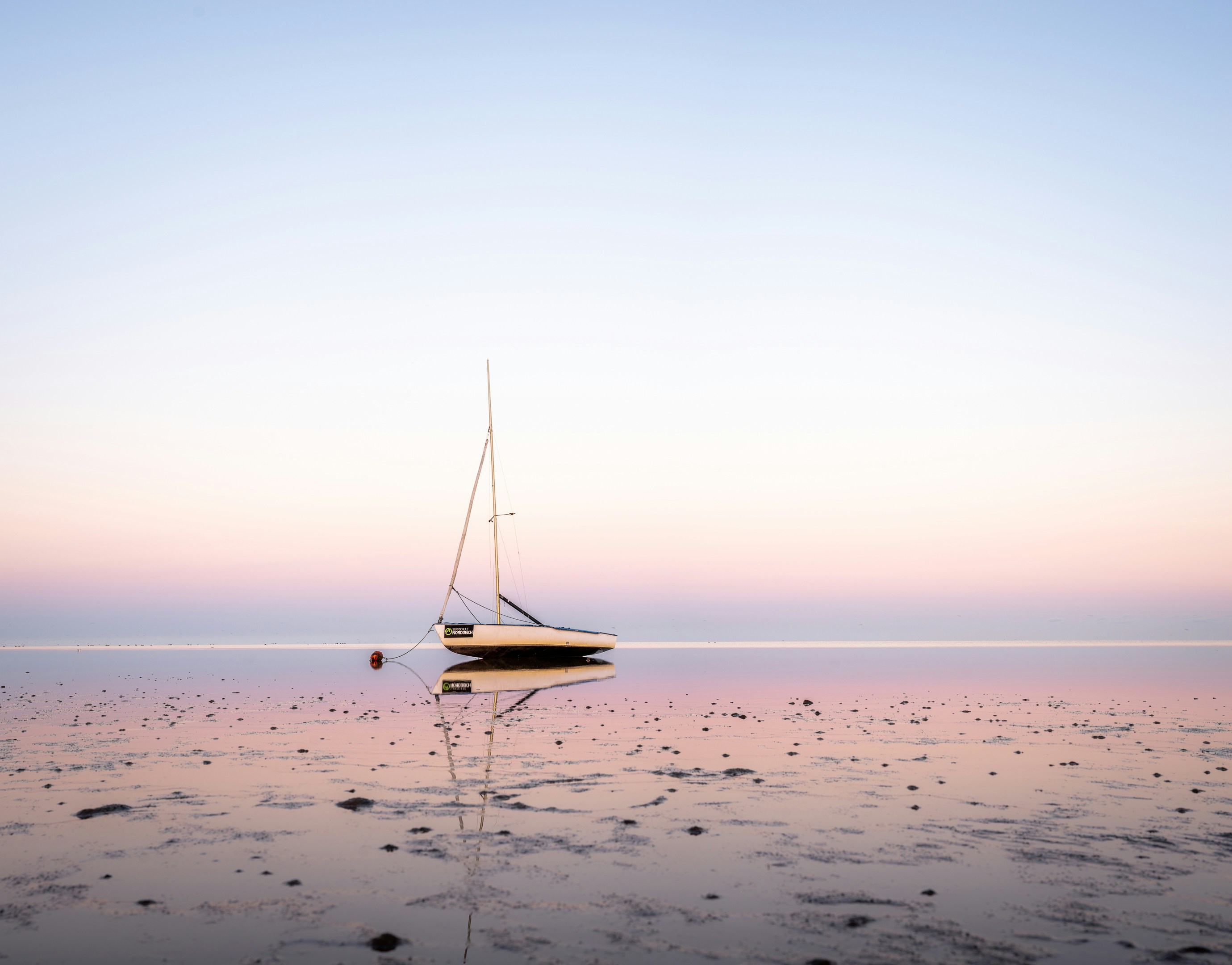 photography of boat, a sailboat in the watt in the North Sea at sunrise