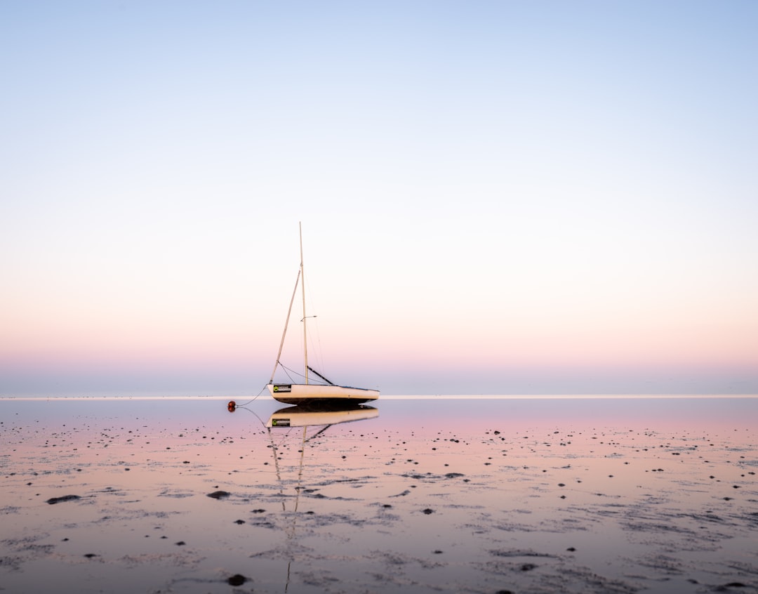 photography of boat, a sailboat in the watt in the North Sea at sunrise