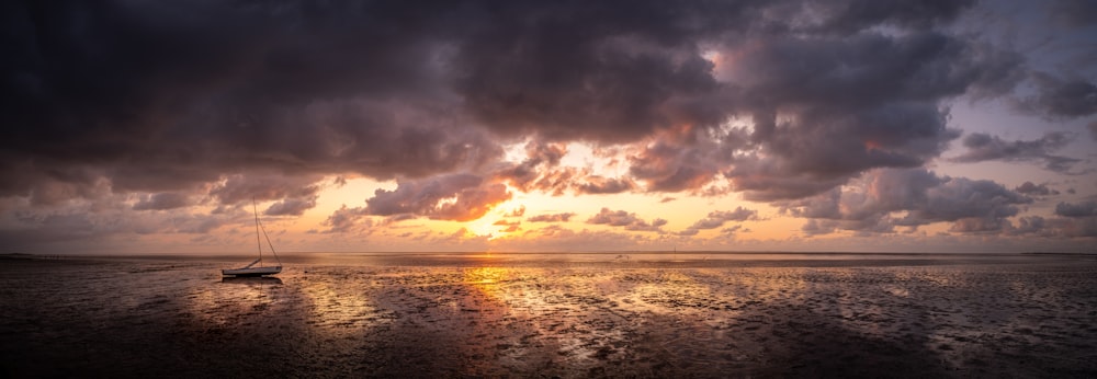 bateau sur le plan d’eau à travers l’horizon au coucher du soleil