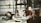 A collection of antique and vintage items displayed on a table, including a brass helmet, a palmistry hand model, various candlesticks, and a selection of small decorative objects. The scene gives a sense of eclectic charm and nostalgia.