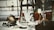 A collection of antique and vintage items displayed on a table, including a brass helmet, a palmistry hand model, various candlesticks, and a selection of small decorative objects. The scene gives a sense of eclectic charm and nostalgia.
