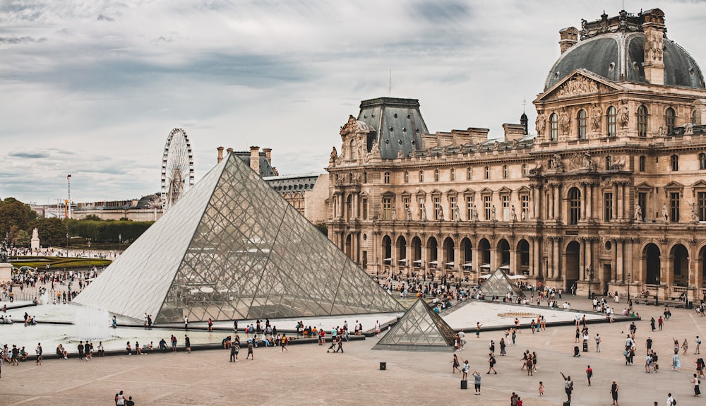 pessoas se reunindo perto do Museu do Louvre durante o dia