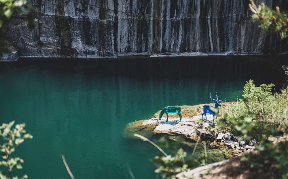 Due decori di cervi verdi e blu sulla riva vicino alla montagna