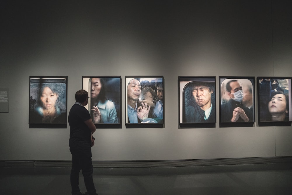 man looking at paintings on wall