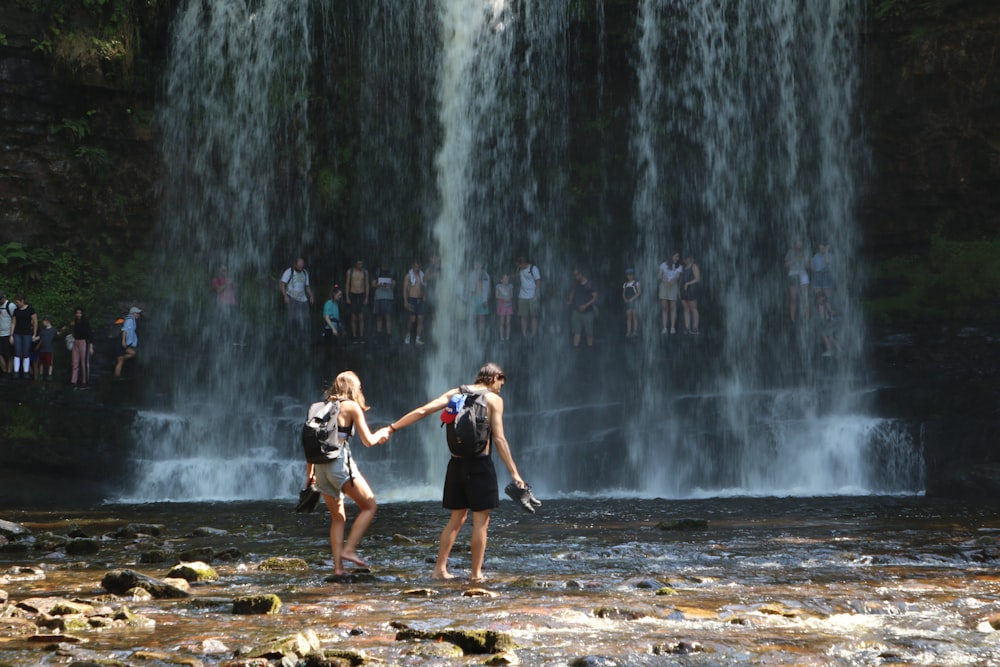man and woman near waterfalls