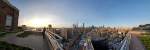 Panoramic rooftop view of downtown Delhi skyline at sunset.