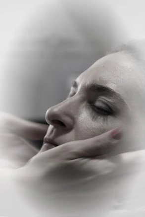 A calm therapy session showing hands gently supporting a relaxed person's shoulder.