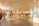 A spacious, well-lit clothing store features neatly organized racks of clothes and accessories. Several mannequins display stylish outfits, and a few customers are browsing through the aisles. The interior is modern with a high ceiling adorned with numerous lights that create a bright and inviting atmosphere.