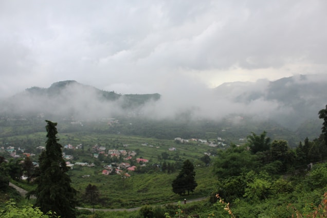 A cozy cottage overlooking rolling green valleys under a misty sky in Vattavada.
