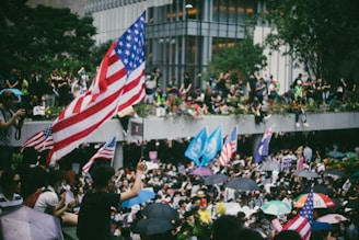a crowd of people holding american flags and umbrellas